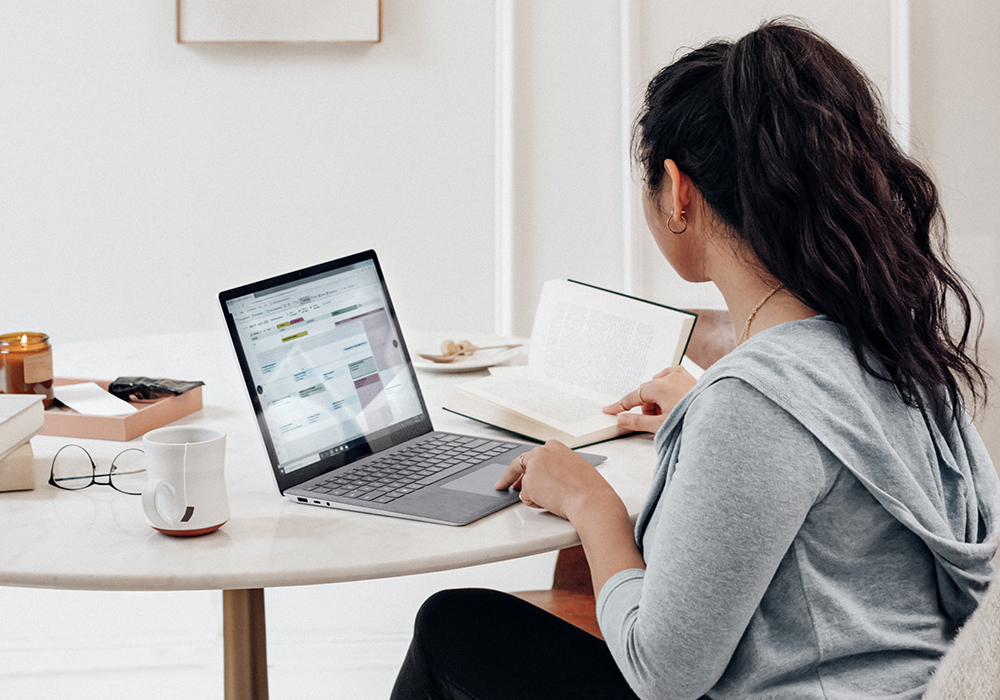 Student sitting at a table studying with a book and a laptop