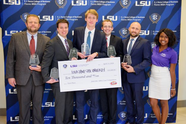 students holding trophies in front of banner