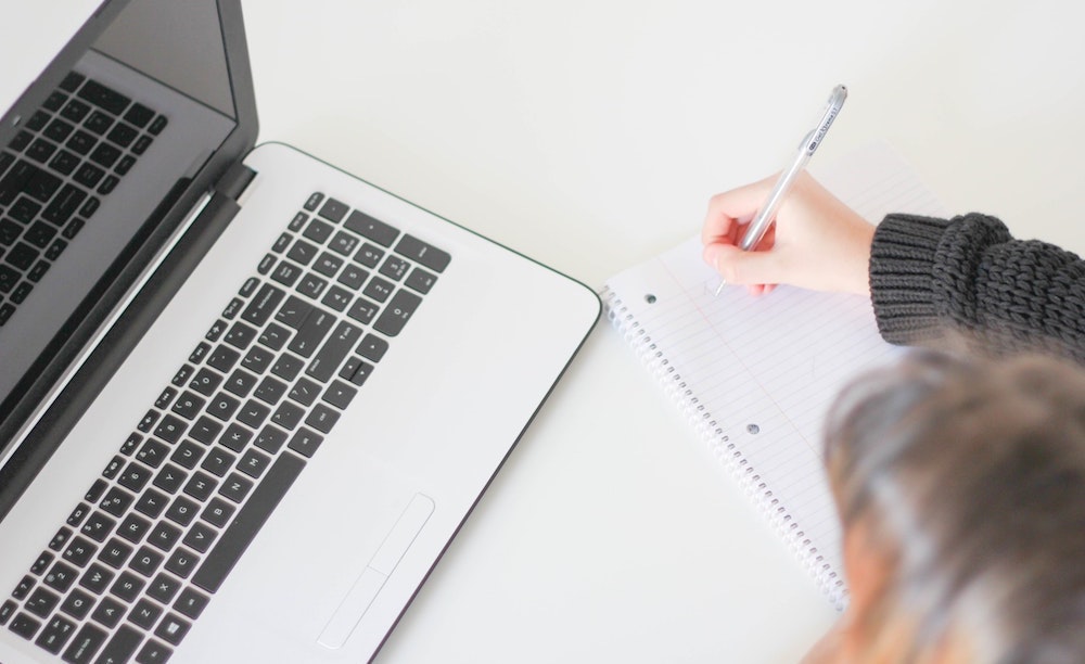 student taking notes by computer