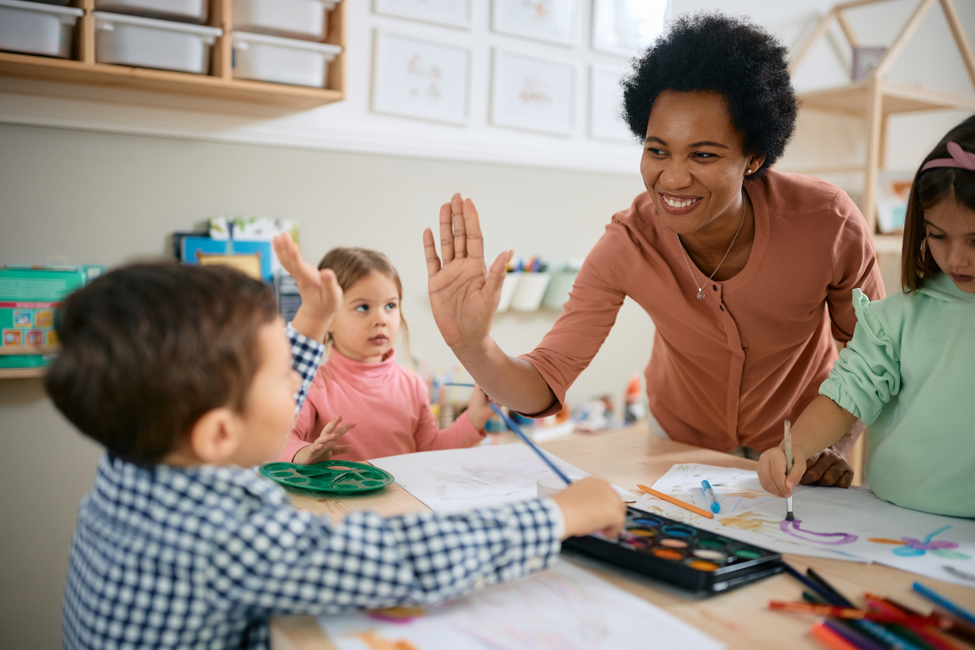 teacher supporting students teacher giving a high five to students in a classroom.